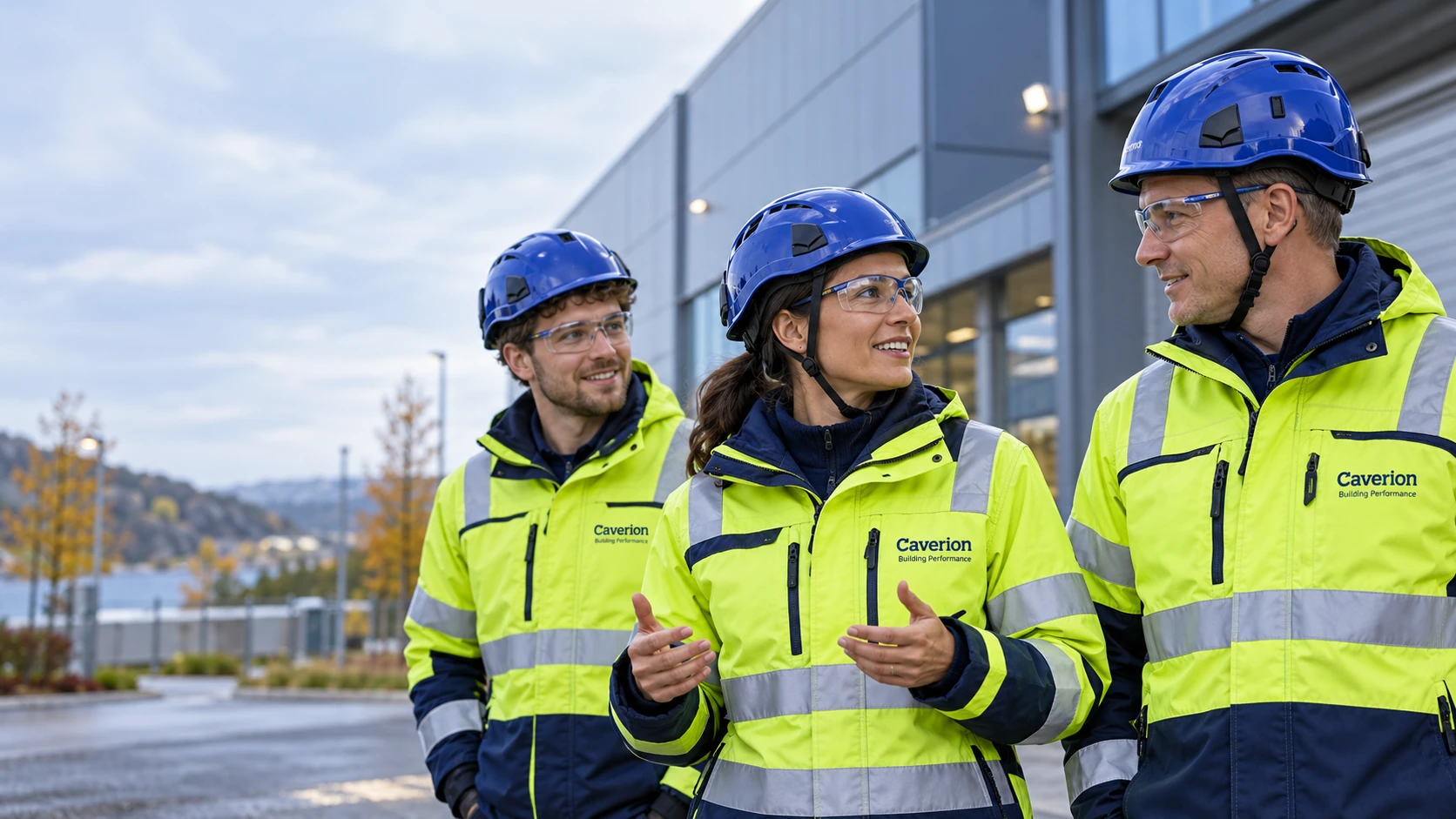 AI-illustrasjon av tre oppdiktede fagfolk i Caverion-arbeidstøy utenfor et industribygg